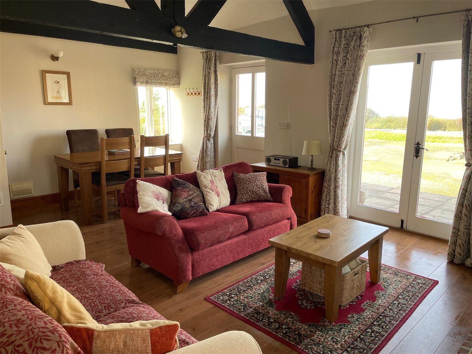 A photo from the entrance looking into the lounge with a double sofa and two single sofas, a gas fire. Onward views towards the kitchen