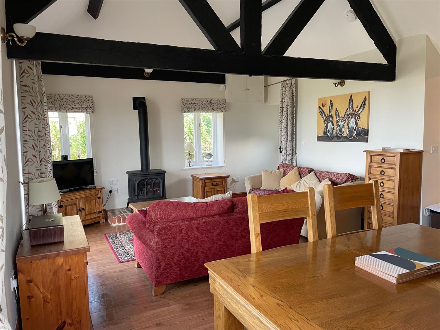 A photo of the lounge and dining room able to seat 4 comfortably with a gas fire, vaulted ceilings and a painting of the donkeys