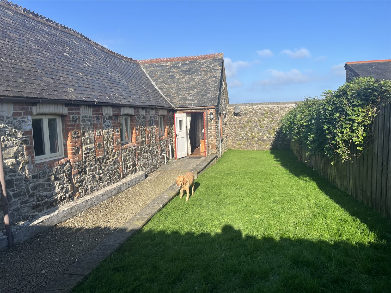 The enclosed back garden, looking towards the property. The garden is laid to lawn with a gravel section. There is an outdoor seating set too.