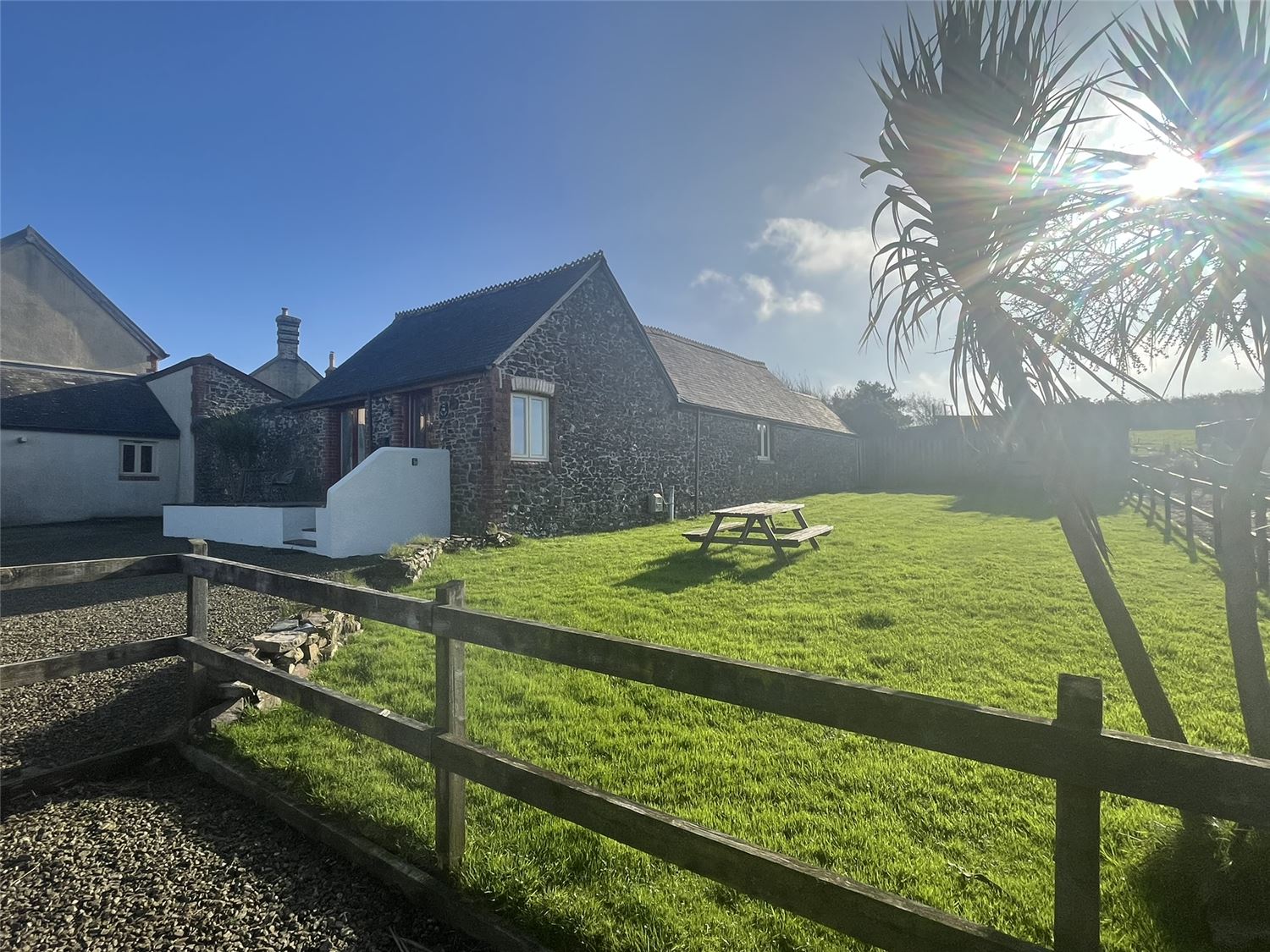 The front view of the barn with the unenclosed side garden. A picnic table is in the garden so that you can sit and enjoy the view with a drink