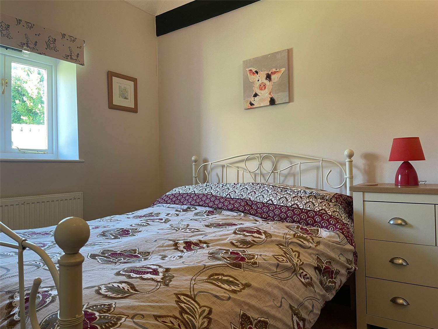 The other bedroom also with a double bed and drawer units. A painting of a pig hangs on the wall as a tribute to the barn's former days as a pig barn.