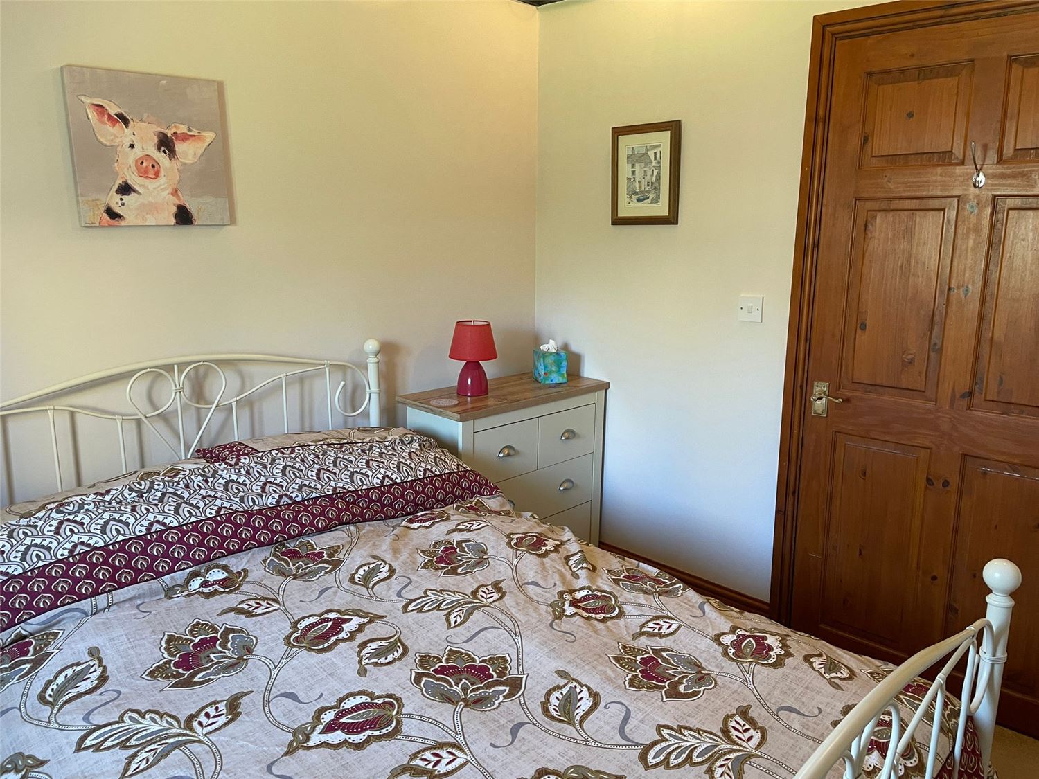 The other bedroom, with a double bed, drawer units and a painting of a pig as a tribute to the barn's former life as a pig barn